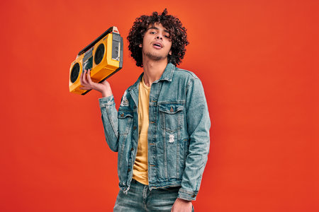 Arabian sexy man holding yellow beat box in hand, listening music. Young student with retro music playerの写真素材