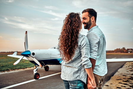 Cheerful young couple standing and hugging near private airplane.の写真素材