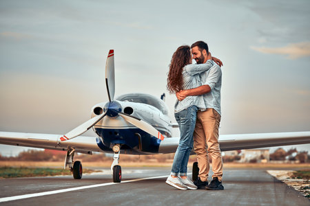 Stylish couple standing near a plane at the airport. Honeymoon. Full lengthの写真素材