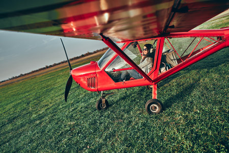 Small light airplane with woman pilot ready to flight on the airport field. Copyspace