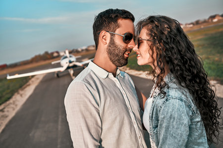 Young beautiful couple kissing on runway with airplane on background.の写真素材
