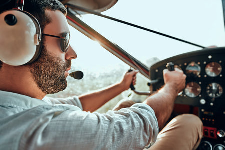 Yong man with beard in an airplane cabin flying a plane. Side view. Close up viewの写真素材