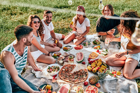 Group of friends having picnic in a park on a sunny day. People hanging out having fun while eating and relaxing. Top viewの写真素材