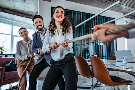 Image of young business team taking competitive advantage playing pulling rope with they work partners. Office setting. Team building conceptの写真素材
