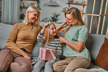 Is this for me? A little daughter unpacks a gift from mom and grandma.の写真素材