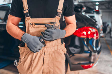 Hand of car mechanic with wrench. Auto repair garage. Close up view.