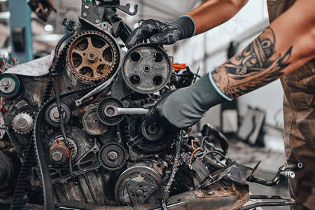 Hands of car mechanic repairs the car engine in auto repair service. Close up view.の写真素材