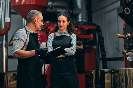 Coffee shop workers checking coffee beans roasting process together and make notes. Selective focus.の写真素材