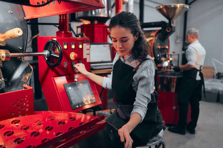 Woman operating coffee roaster in his factory.の写真素材