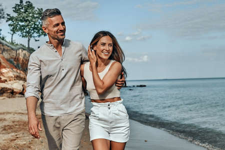 Happy attractive couple walking on beautiful sunny beach. Copy spaceの写真素材