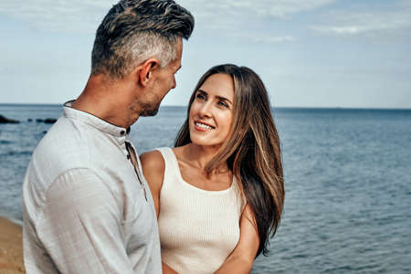 Image of a positive smiling optimistic beautiful adult loving couple walking outdoors near the sea in nature. Close up view.の写真素材