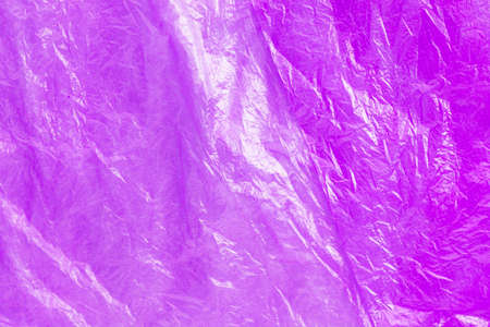 Close up texture of bright purple plastic garbage bag. Crumpled cellophane. Violet polyethylene film background. Ecology problem.の写真素材