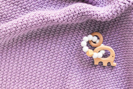 Hand knitted plaid and baby wooden teether bracelet, elephant with rubber beads. Soft blanket. Childbirth. Newborn concept. Flat lay, top view with copy space.の写真素材