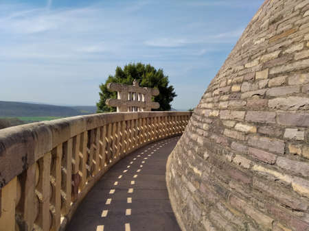 A curved narrow path on the sanchi stupa. Blue sky and trees are also visible.