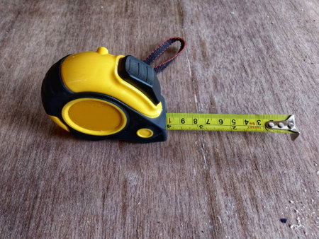 Yellow measuring tape on wooden background. a tool for measuring the length of wood.