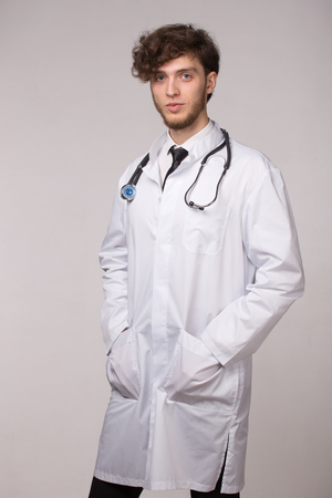 Portrait of confident young smiling medical doctor with sthetoscope on light gray backgroundの写真素材