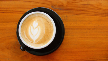 Coffee cup with latte art on wooden table background.の写真素材