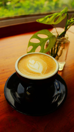 Cup of coffee with latte art on the wooden table.の写真素材