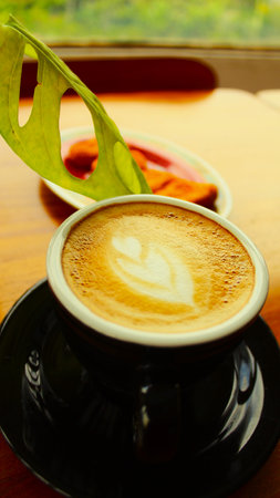 Coffee cup and leaf on wooden table in coffee shop.の写真素材