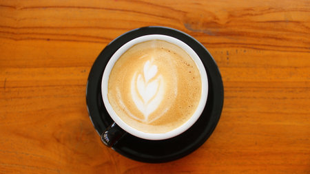 Coffee cup with latte art on wooden table background.の写真素材