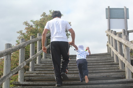 Young father and son holding hands & walking up wooden steps. family time concept with youthful father talking his son up the stairsの写真素材