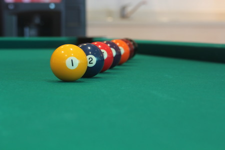 yellow snooker ball with number one on it with other colorful balls placed in a row on a table -...