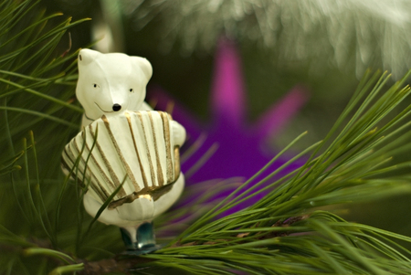 Vintage glass Christmas tree toy: cute polar bear with accordion close-up against the background of green branches. Blurred background.の写真素材