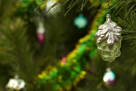 vintage glass Christmas ornament - transparent golden grapes with silver leaves - on a background of a blurred Christmas treeの写真素材