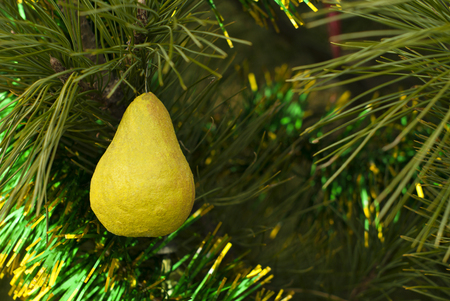 retro Christmas ornament - yellow pear of papier-mÃ¢chÃ©  - on a background of a blurred Christmas treeの写真素材