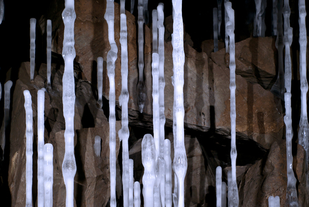 thin high icy columns in a cave on the background of brown stonesの写真素材
