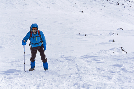 climber goes up the snow-covered mountain slopeの写真素材