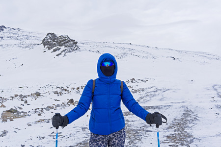 girl traveler or skier in warm clothes, windproof mask and windproof glasses in the winter mountainsの写真素材