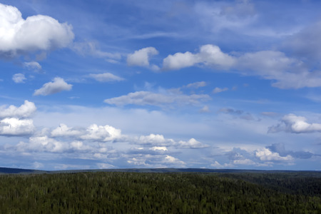 heavenly landscape - a blue sky with clouds over a wooded hilly land with a bird's eye viewの写真素材