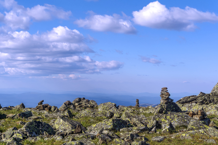 bright landscape of a high-altitude plateau with folded travelers pyramids cairns of stones under a blue sky with cloudsの写真素材