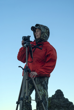 girl in hiking clothes looks into the distance, preparing to take a picture of the camera on a...