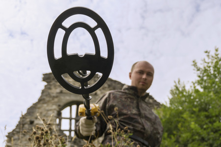 man searches with a metal detector in the ruins of the building, a view from the ground from the...