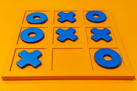 board game tic-tac-toe, blue figures on a bright orange field, the result of the match - a drawの写真素材