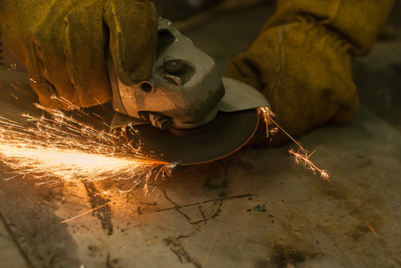 metalworking with a hand-held circular saw, close up, the disk is blurred in motion, many sparks are visibleの写真素材