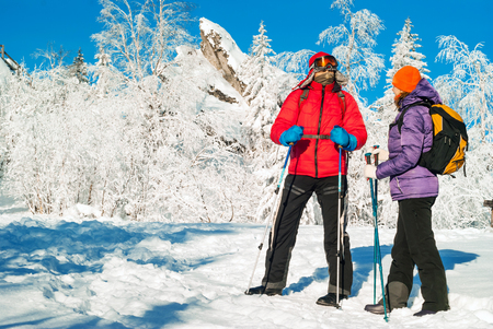 man and woman hikers with backpacks and nordic walking poles in a frosty winter landscapeの写真素材