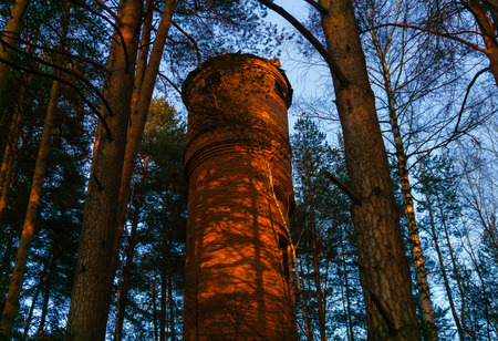 old abandoned brick water tower in the forest in the evening lightの写真素材