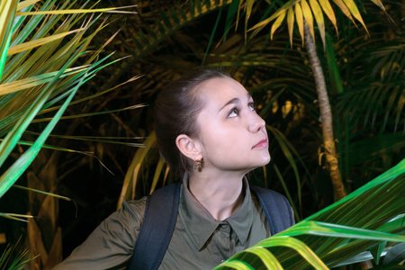 girl traveler in the jungle among the tropical vegetation looks to the side upの写真素材