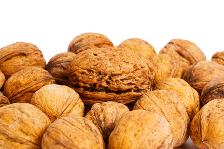heap of walnuts, one of which is more than the others, on a white background