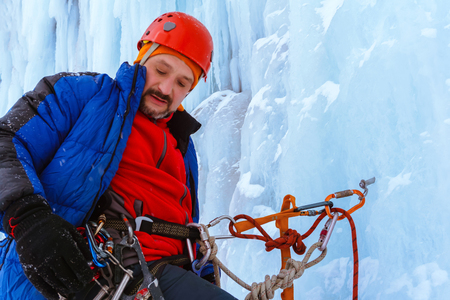 ice climber is fixed on the vertical surface of the glacier with safety anchorの写真素材
