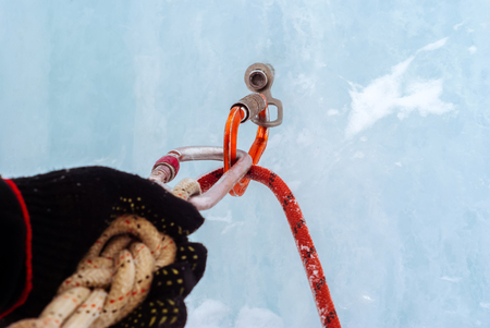 Ice climbing anchor with ice screw, safety rope, carabiners and climber`s arm, closeupの写真素材