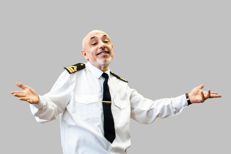 happy elderly man in an officerâs sea uniform smiles and shrugs; isolated on gray backgroundの写真素材