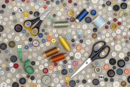 background - multicolored buttons and accessories for sewing lie on a rough fabricの写真素材