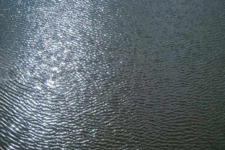 background - shiny glossy water surface with ripples and sky reflection