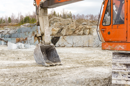 orange dirty excavator stands in a quarry for the extraction of marbleの写真素材