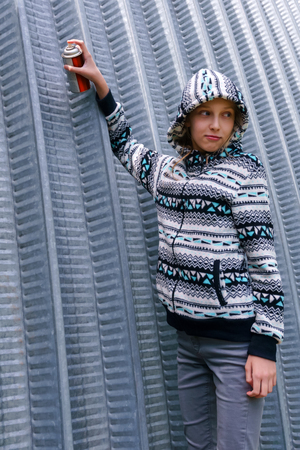 teen girl with spray paint looks around, about to write graffiti on the wallの写真素材