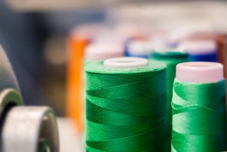 bobbin of green thread in the clothing industry on a blurred background